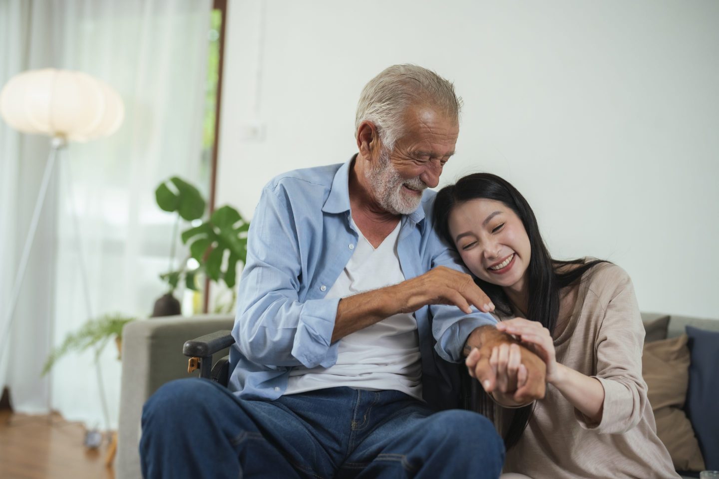 A senior man in wheelchair with a caretaker at home.
