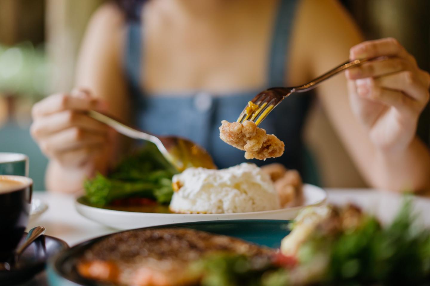 A woman holds a fork with a bite of food