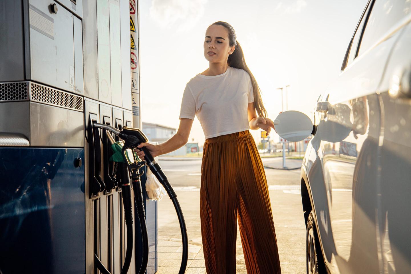 woman fills up car at gas station