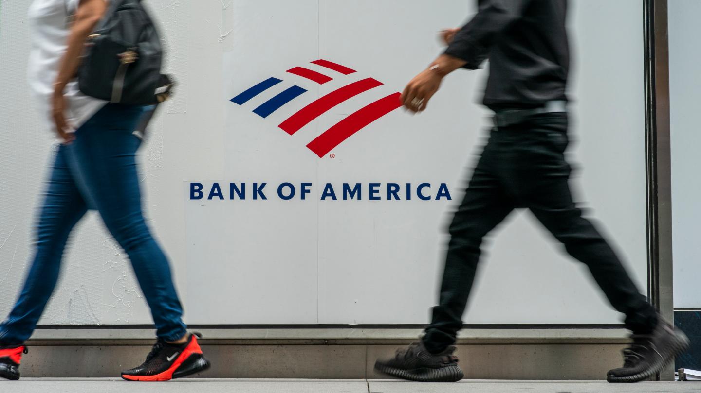 Two people walk past the Bank of America logo
