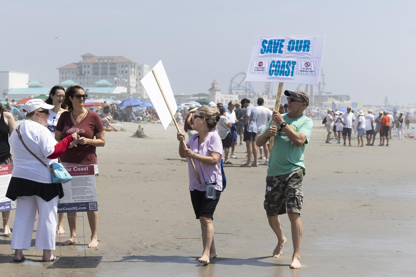 Ocean City residents MaryClare and Dave Shuster hold signs reading "Save Our Coast"