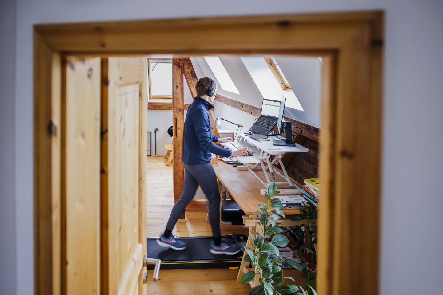 A person walks on a treadmill at a desk while working from home