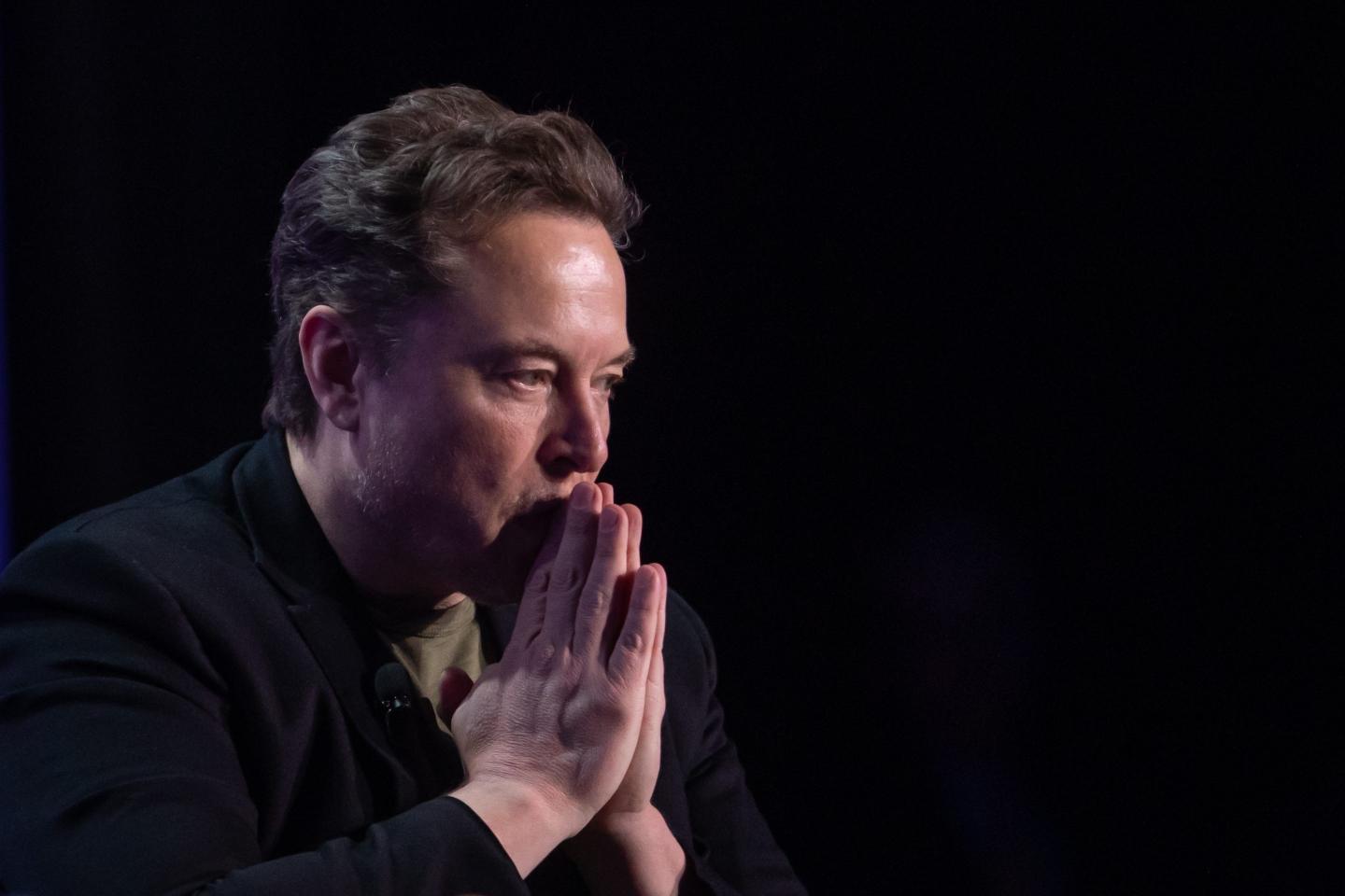 Elon Musk holds hands in front of face