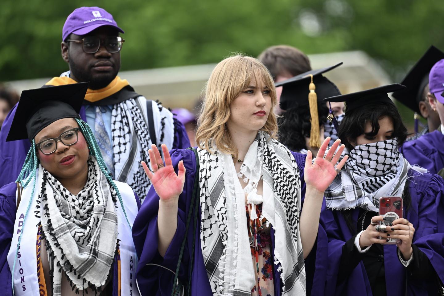 NYU students in graduation robes wear keffiyehs and stand in protest of Israel's attacks on Gaza.