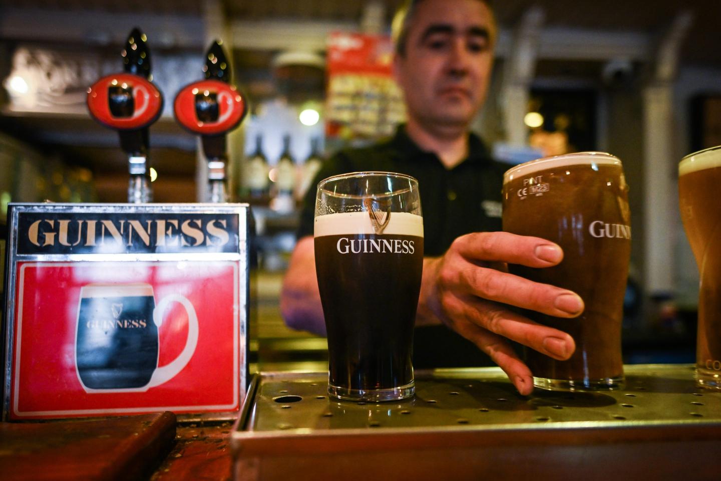 a bartender serving glasses of Guinness