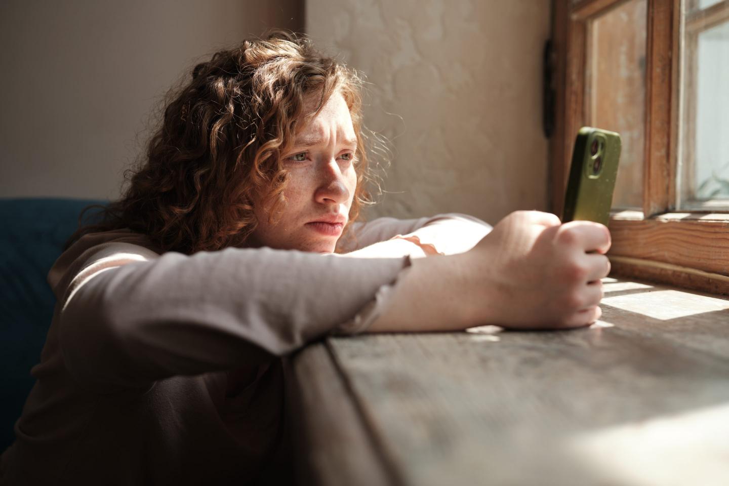 Sad redhead gen z girl on her phone