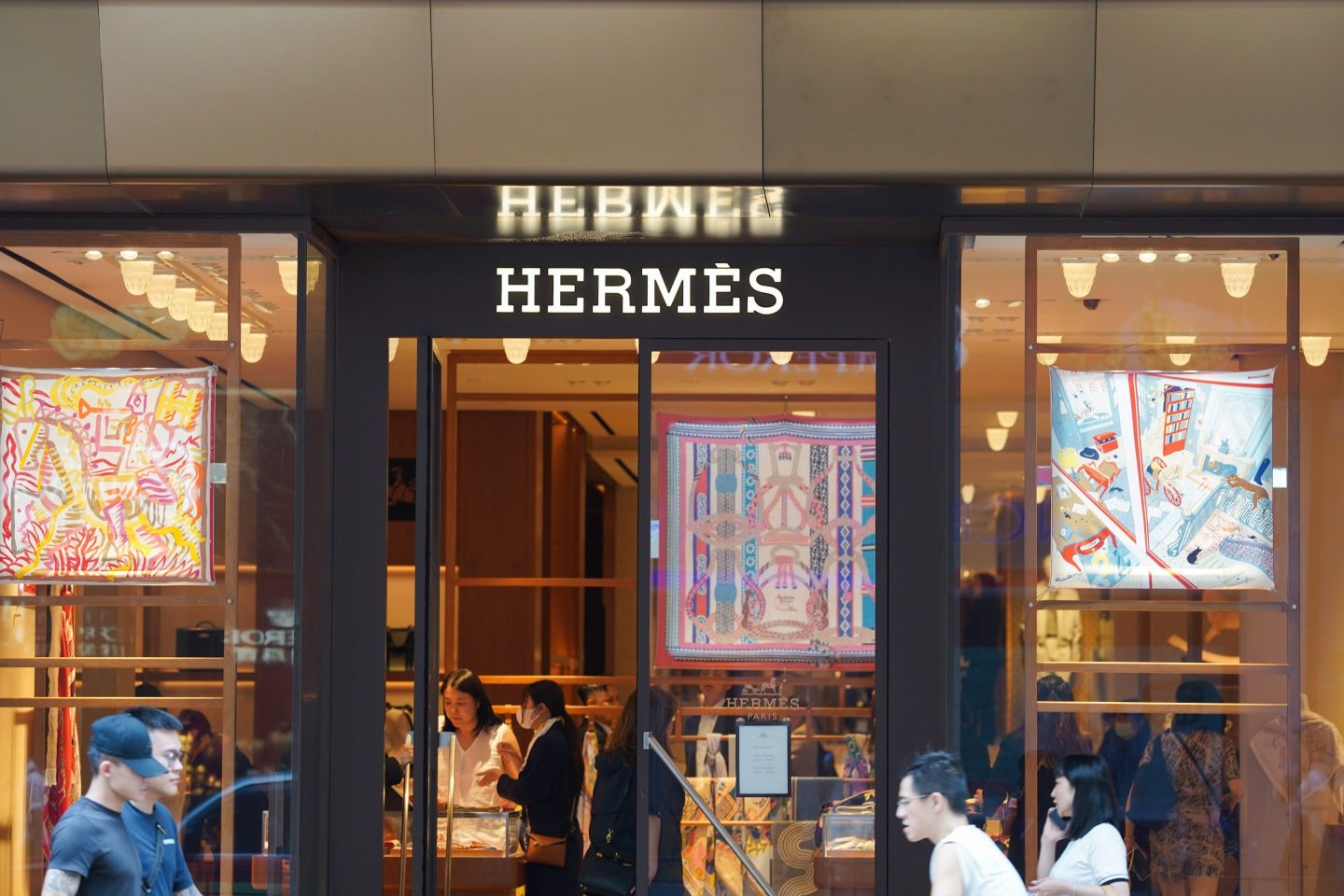 Pedestrians walk past the French luxury design house Hermès
