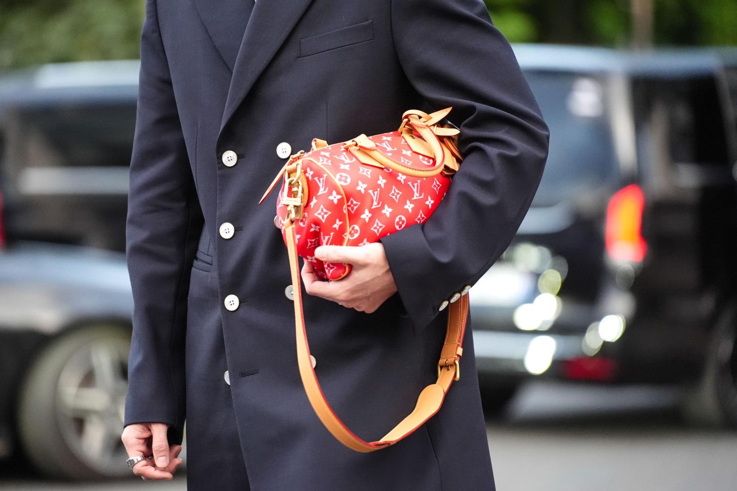 A guest wears Louis Vuitton red leather bag, outside Louis Vuitton, during the Paris Fashion Week Menswear Spring/Summer 2025 on June 18, 2024 in Paris, France.