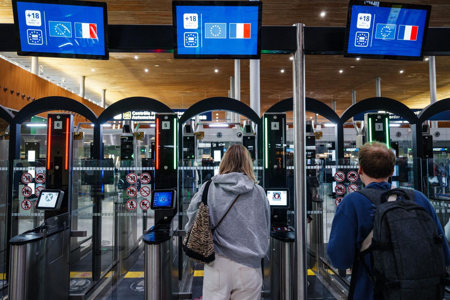 EDITORS NOTE: Graphic content / Police officers help passengers to go through a facial recognition verification system at the Terminal 2E of Roissy-Charles de Gaulle airport on the day of the presentation of the measures to ease border controls for foreign visitors for the upcoming Paris 2024 Olympic Games, in Roissy-en-France, north of Paris, on July 3, 2024. (Photo by Dimitar DILKOFF / AFP) (Photo by DIMITAR DILKOFF/AFP via Getty Images)