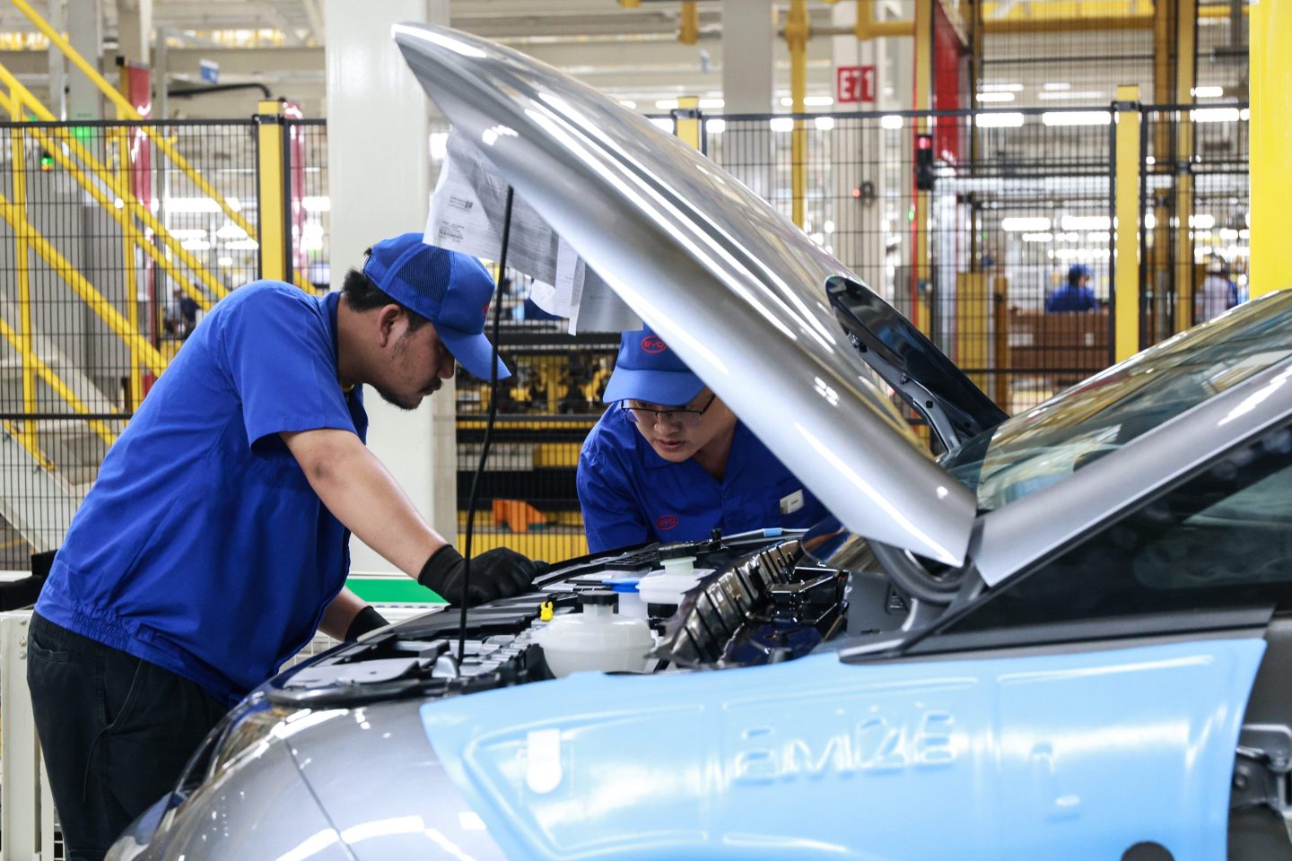 Workers check under the hood of a BYD Dolphin at the company's new plant in Thailand on July 4, 2024.