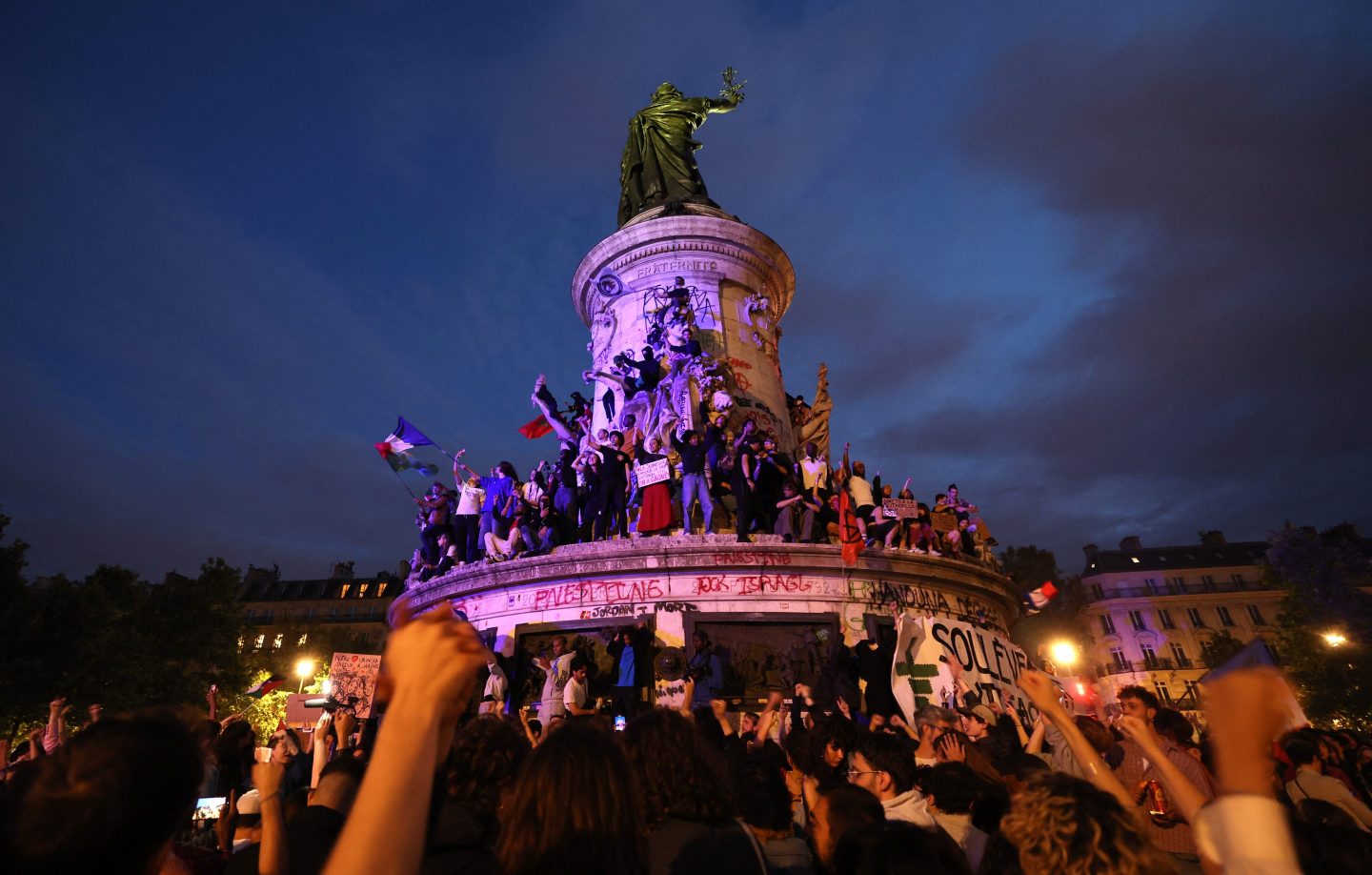 Participants wave French national tricolors during an election night rally following the first results of the second round of France's legislative election.