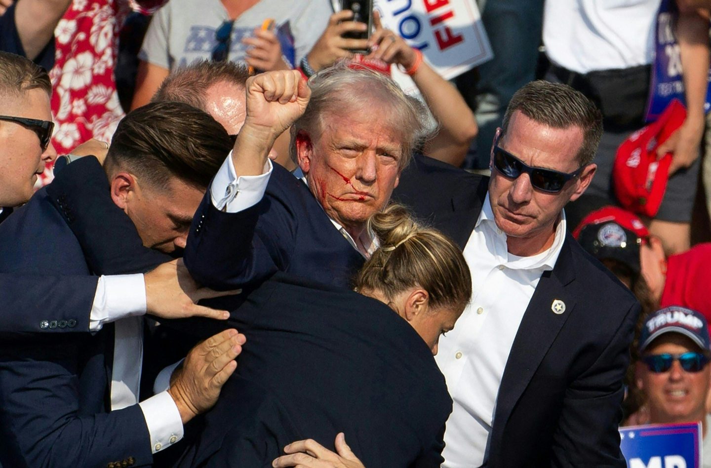 Trump raises his first with blood on the side of his face in the wake of the assassination attempt.