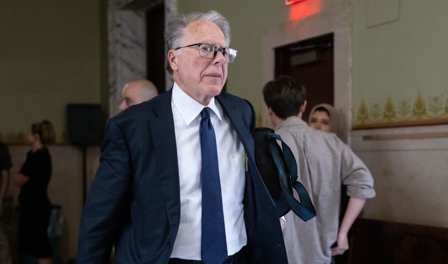 Wayne LaPierre walks down court building hallway