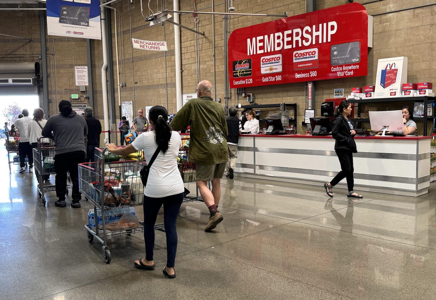 Customers walk by the membership counter at Costco.