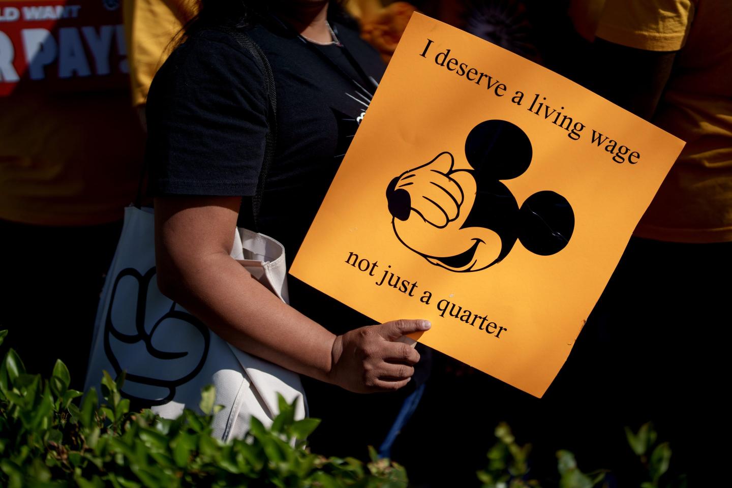 A Walt Disney Co. employee supporter holds a sign during a rally in Anaheim, California, US, on Wednesday, July 17, 2024. Last month 1,700 Disneyland Resort