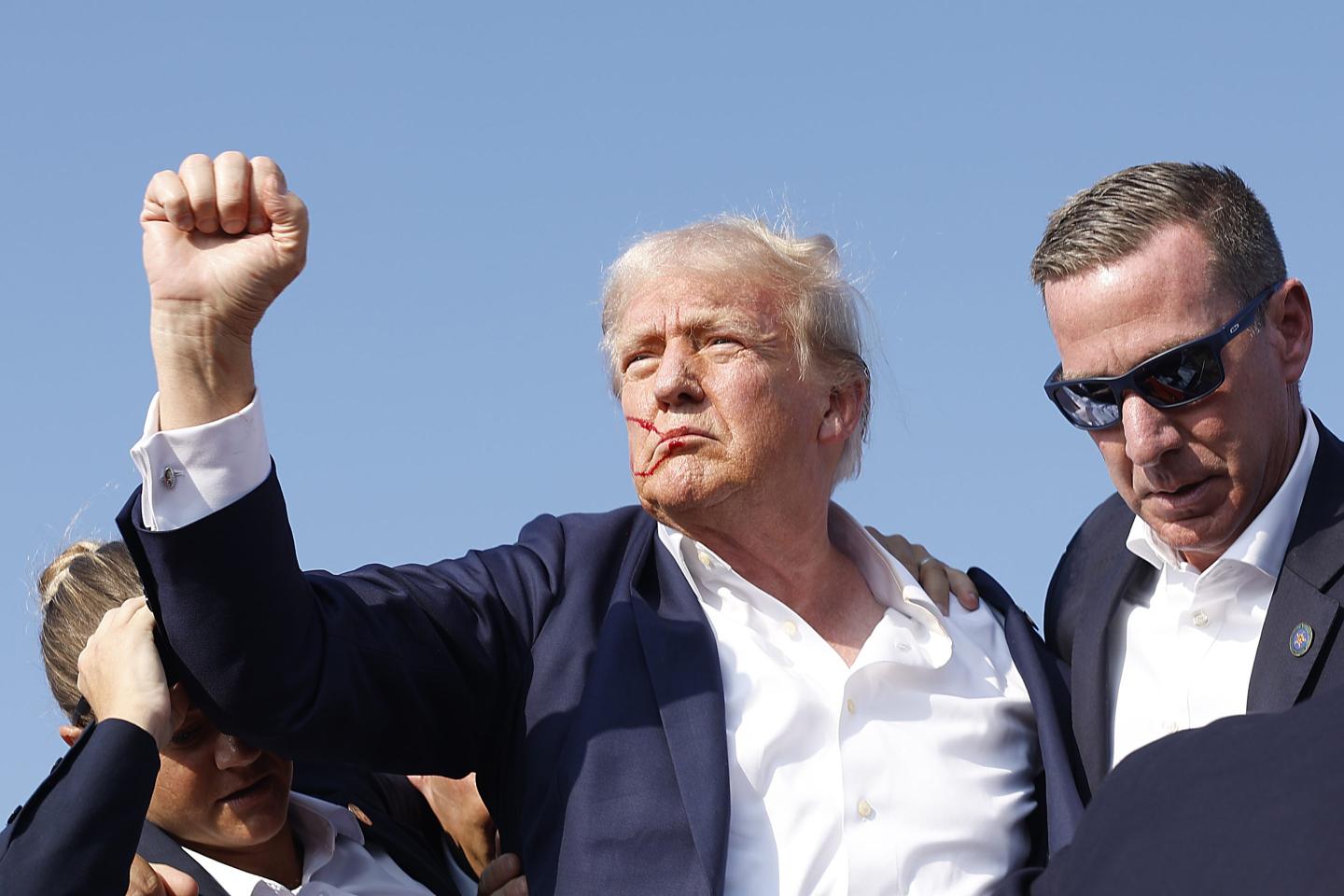 Donald Trump raises his fist after an attempt on his life failed.