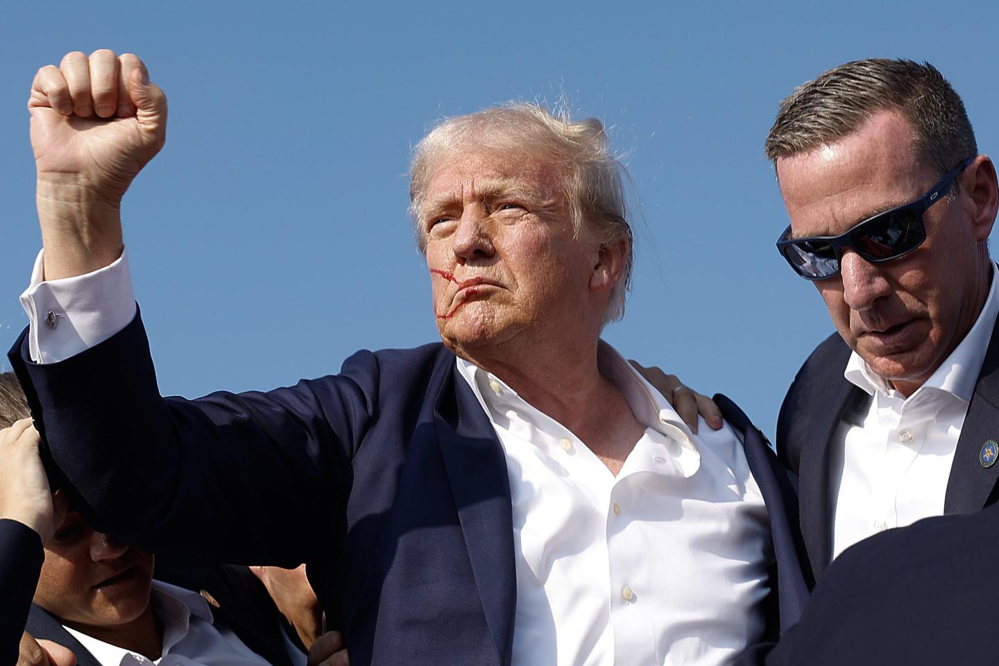 Republican presidential candidate former President Donald Trump pumps his fist as he is rushed offstage by U.S. Secret Service agents
