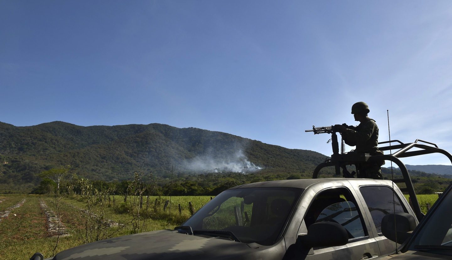 A soldier in the back of a pickup truck witnesses a smoke plume in Jalisco, Mexico