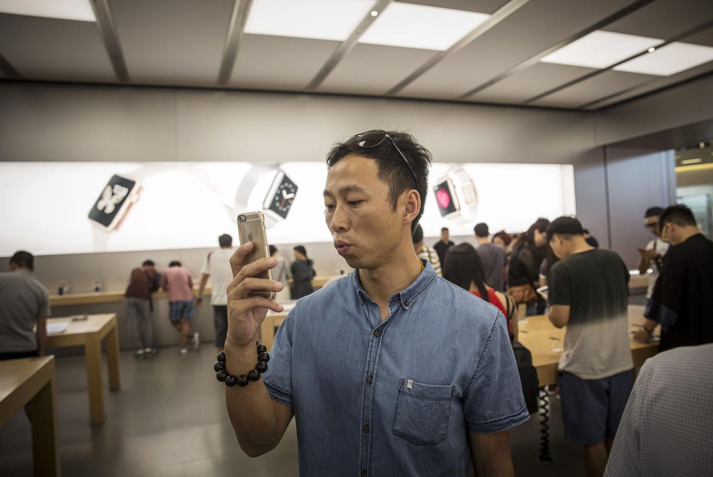 A Chinese man takes a picture with his new iPhone in an Apple Store