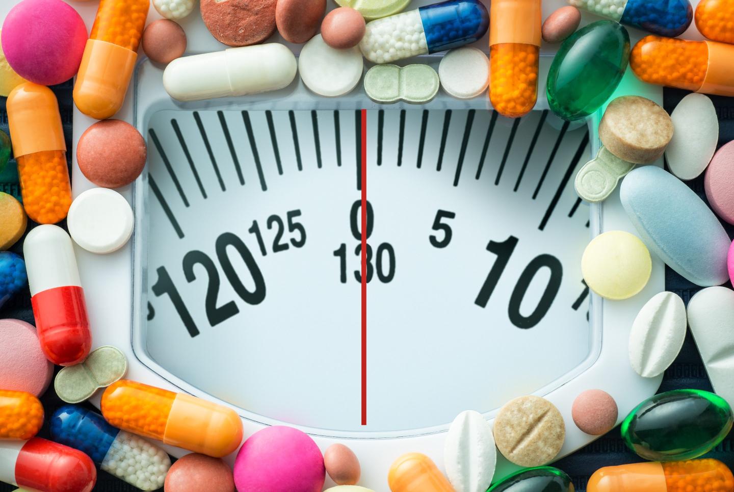 A bathroom scale is surrounded by colorful pills.