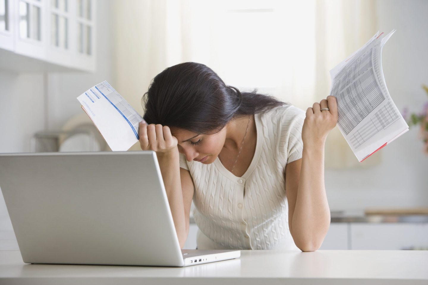 Woman looking at her laptop with her head in her hands