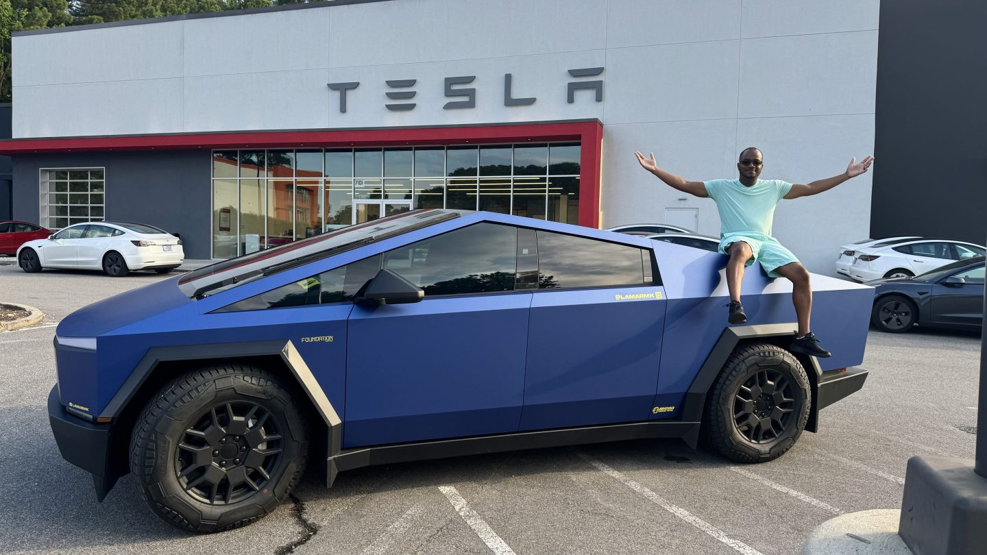A man with arms outstretched sitting on a Tesla Cybertruck