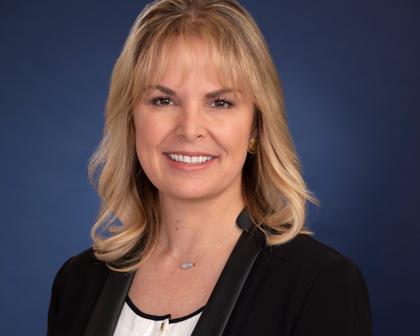 a blonde woman in professional dress posed for a headshot portrait