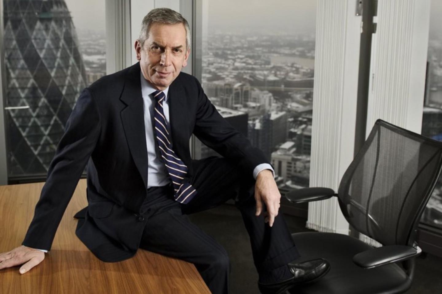 Terry Smith of Fundsmith sits on a table in a skyscraper verlooking the Gherkin in London.
