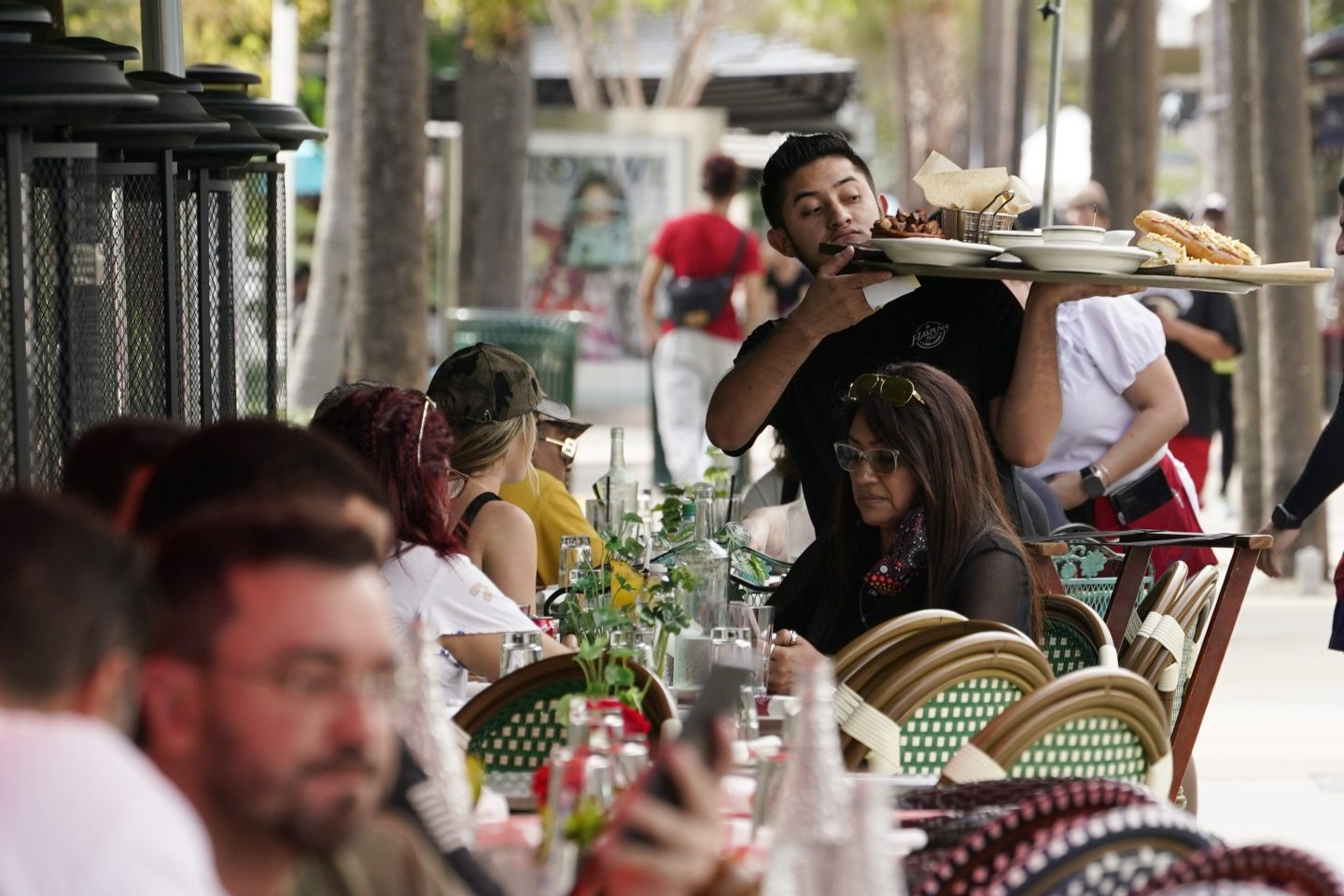 A waiter delivers food to patrons at a restaurant, Jan. 21, 2022, in Miami Beach, Fla.
