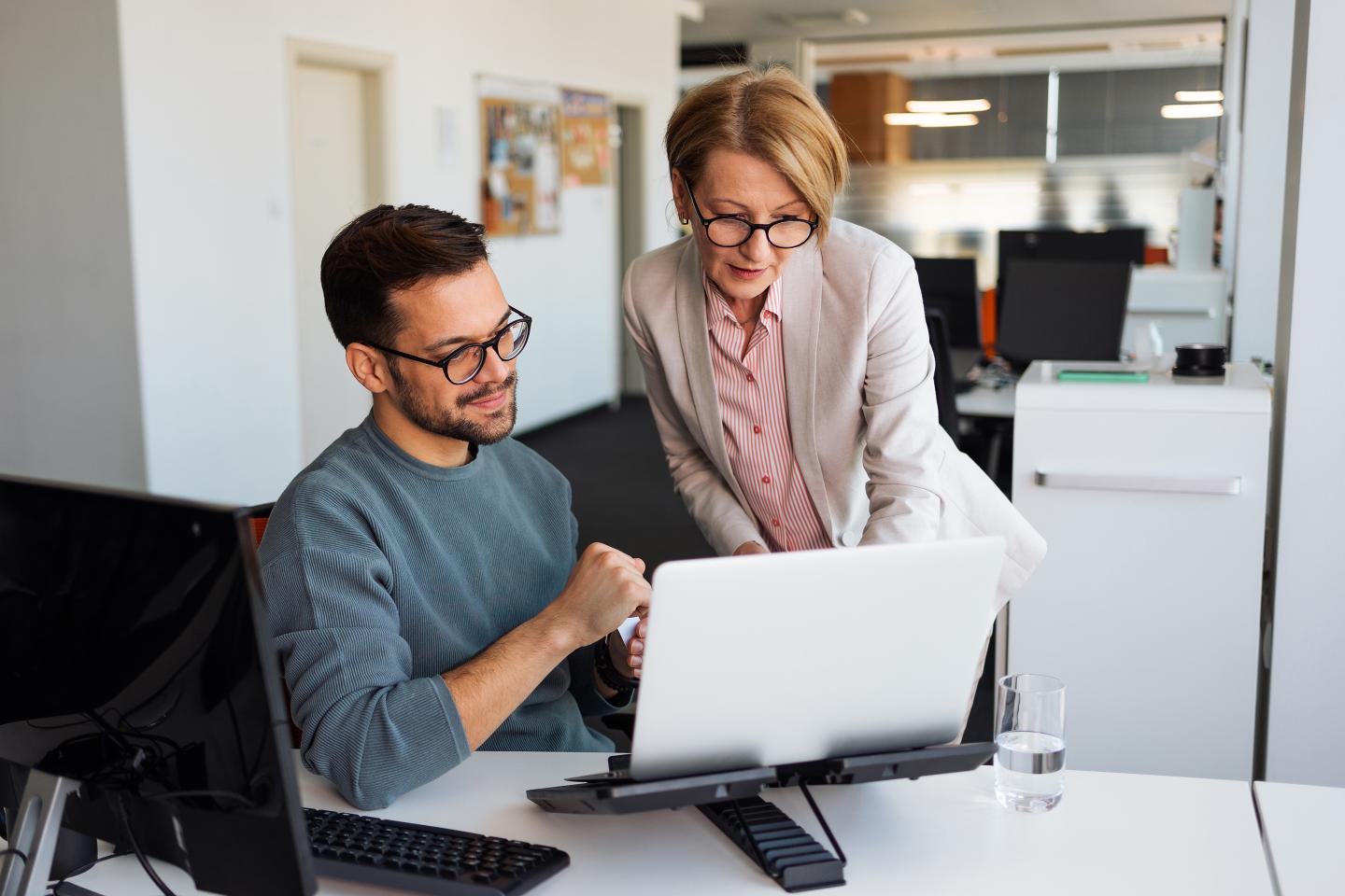 A female senior manager looking at screen of a younger colleague.