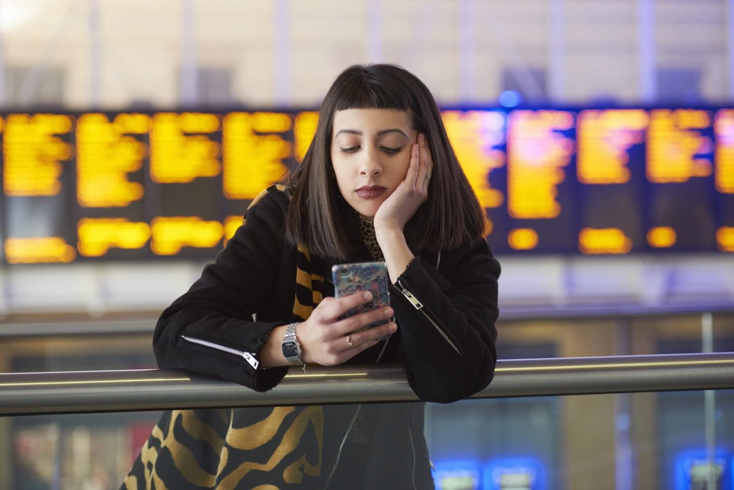 a person looking down at their phone with screens at the back