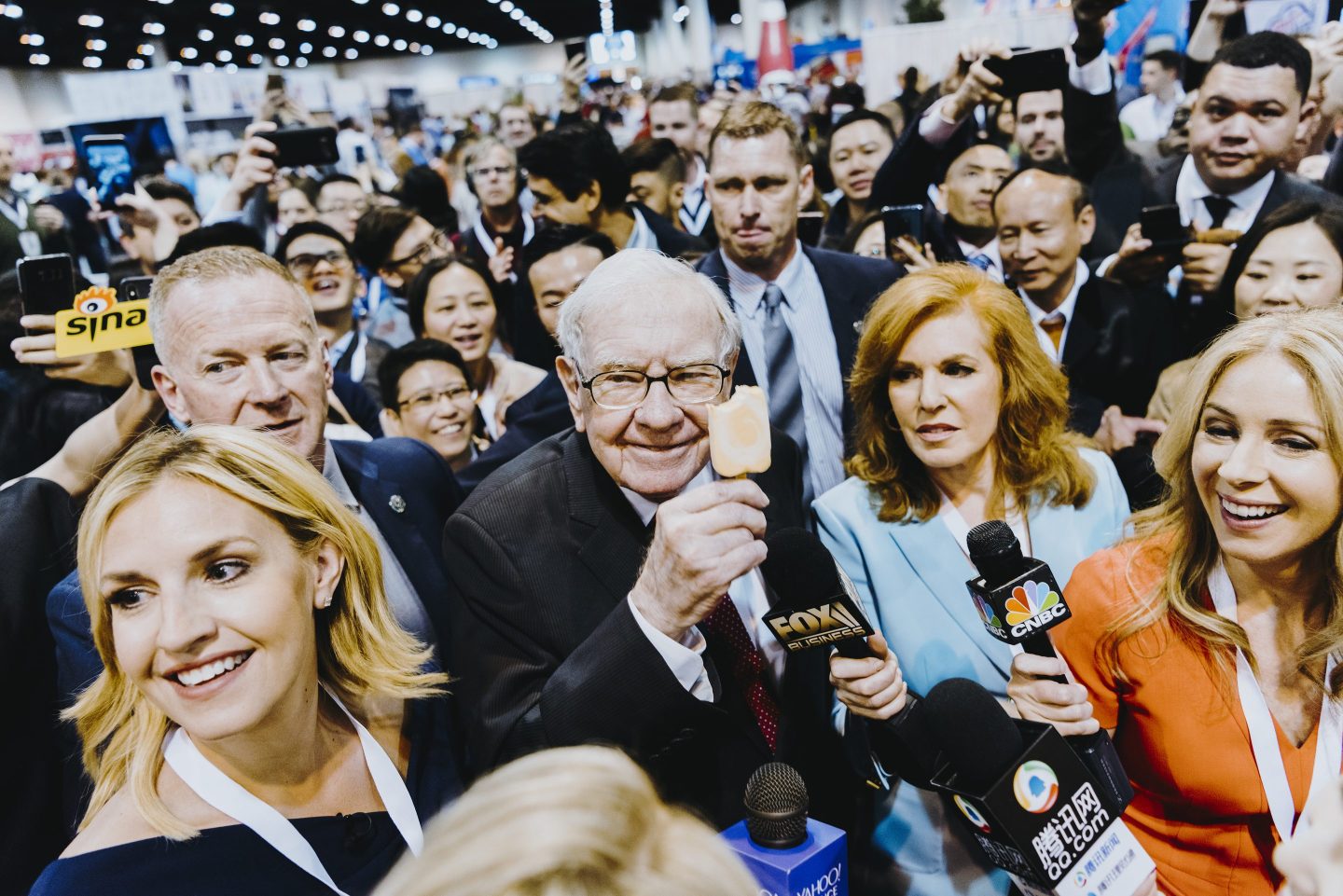 Warren Buffett eating an ice cream pop while surrounded by a crowd