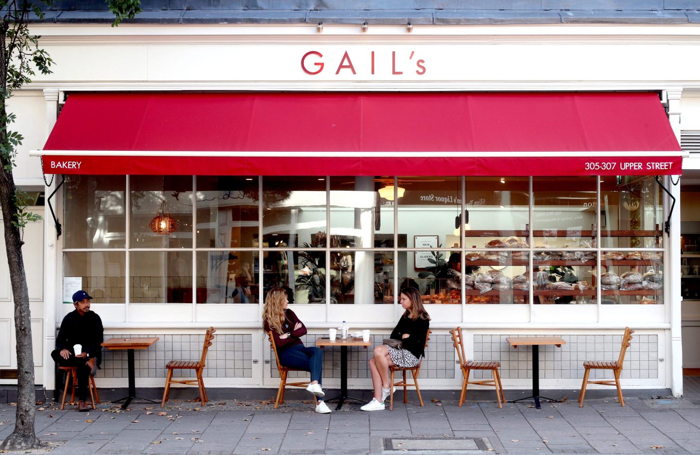 Customers observe social distancing as they sit outside a branch of Gail's bakery on Upper Street in Islington, North London.