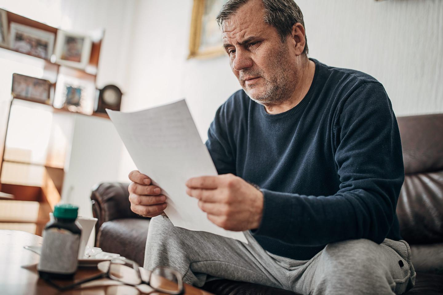 A man reads a letter and looks concerned