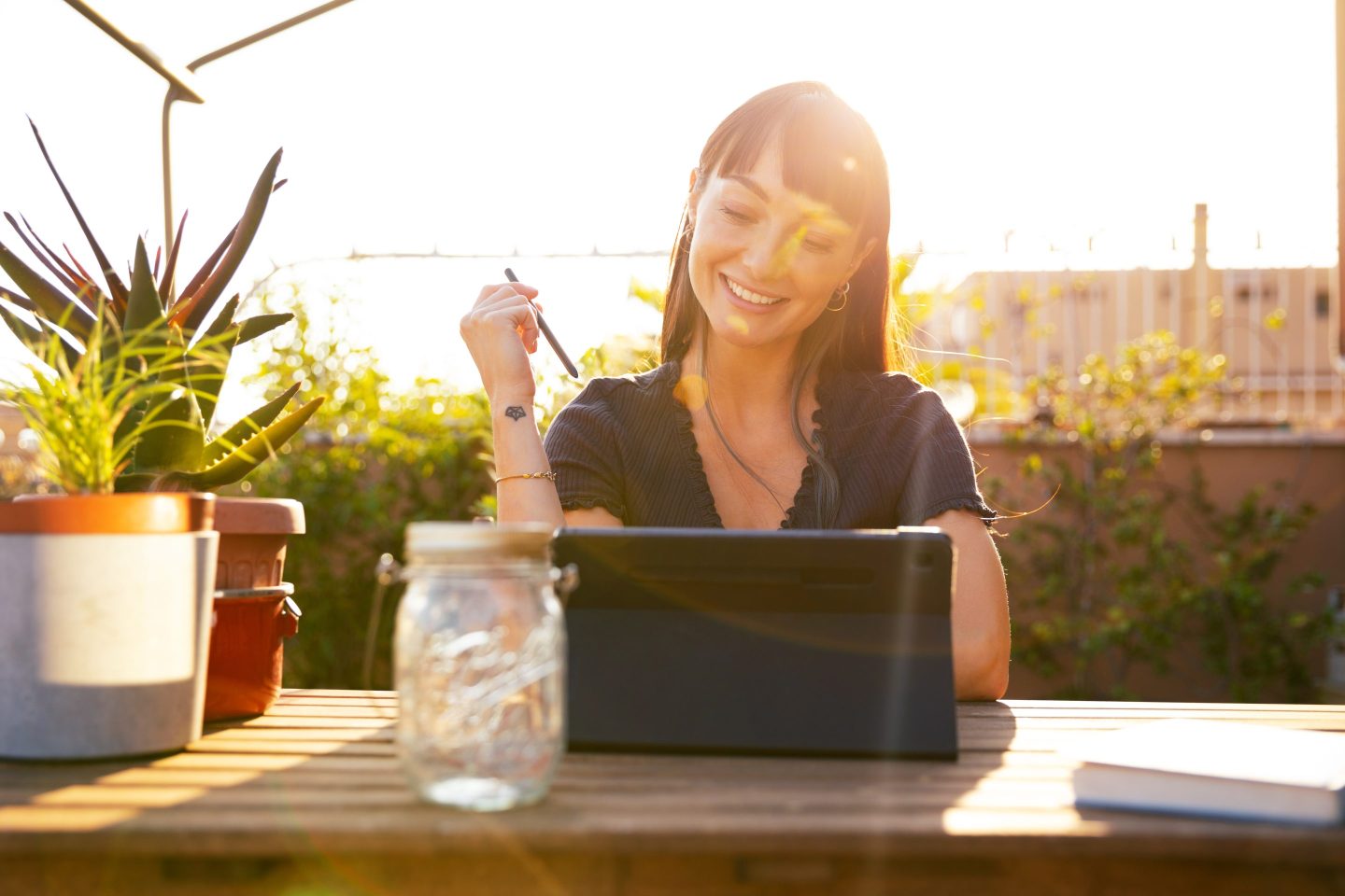 Young woman using tablet on terrace at sunset