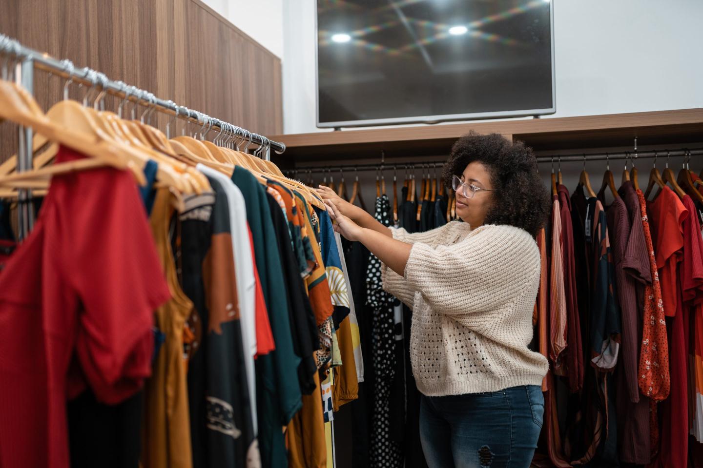 A person sifts through a rack of clothing.