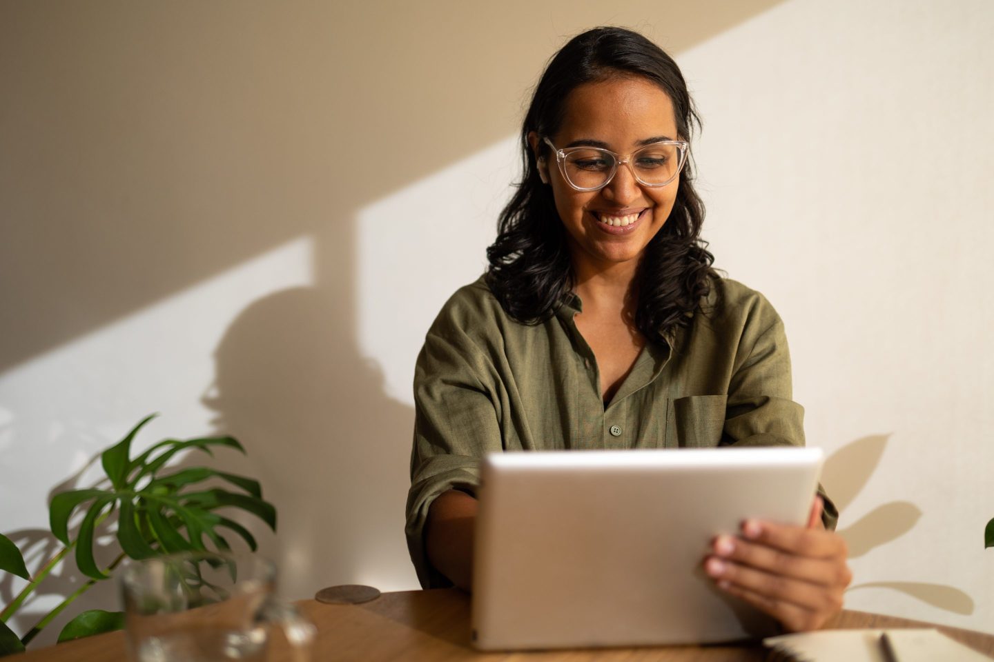 Woman smiling while working from home on her digital tablet