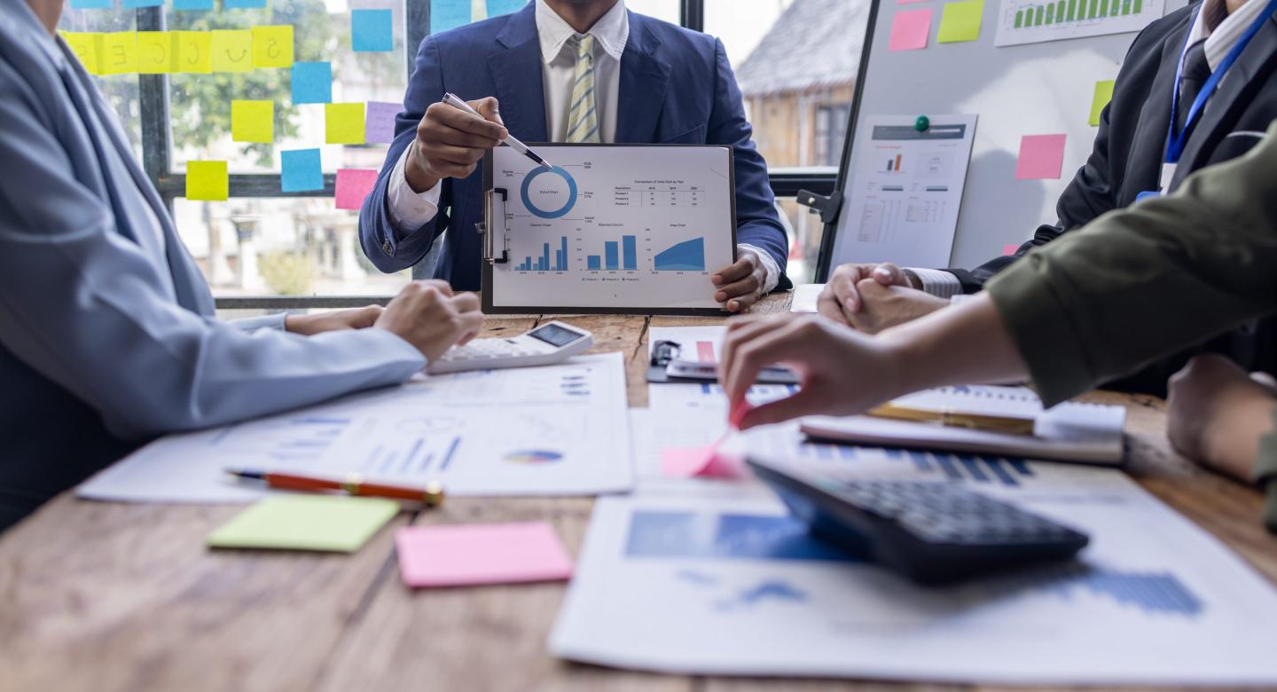 Group of business people look over graphs and chart