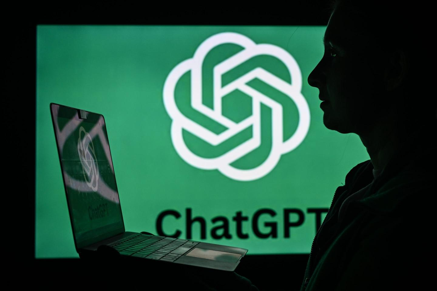A man using a computer in front of the ChatGPT logo