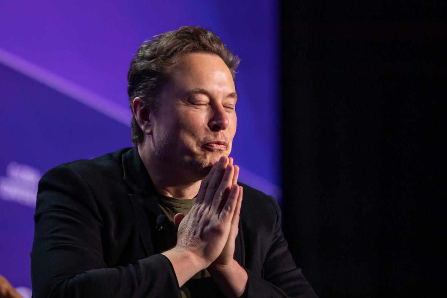 Elon Musk putting hands together