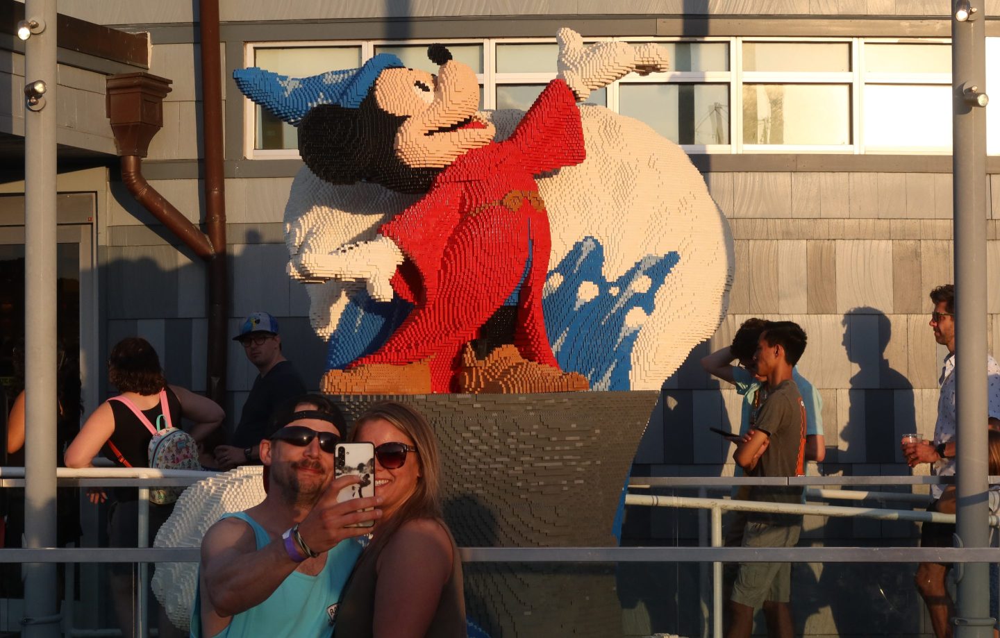 People take a selfie in front of a Lego Mickey Mouse on display at their store at Disney Springs at Walt Disney World