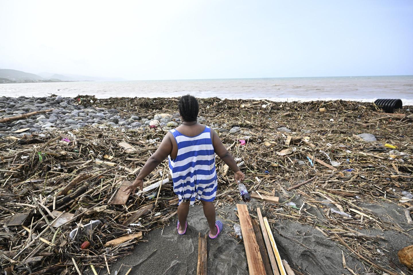 woman looks at debris on a beach