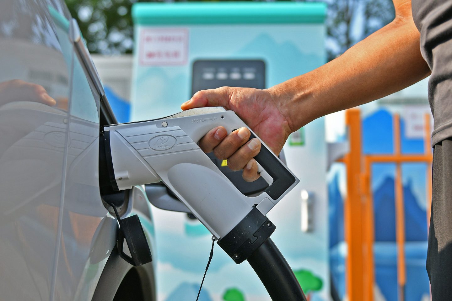 A person plugs in their electric vehicle.