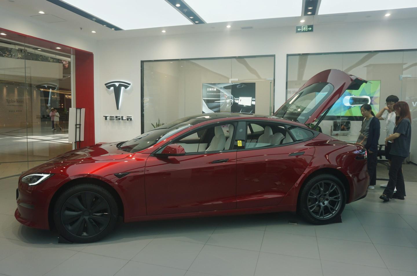 People are looking at a Tesla electric car at a Tesla sales store