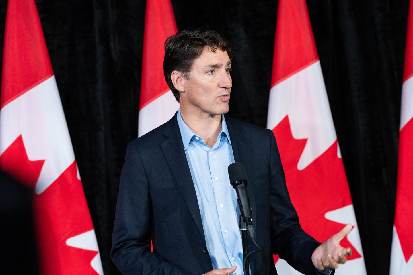 Justin Trudeau speaks next to Canada flags