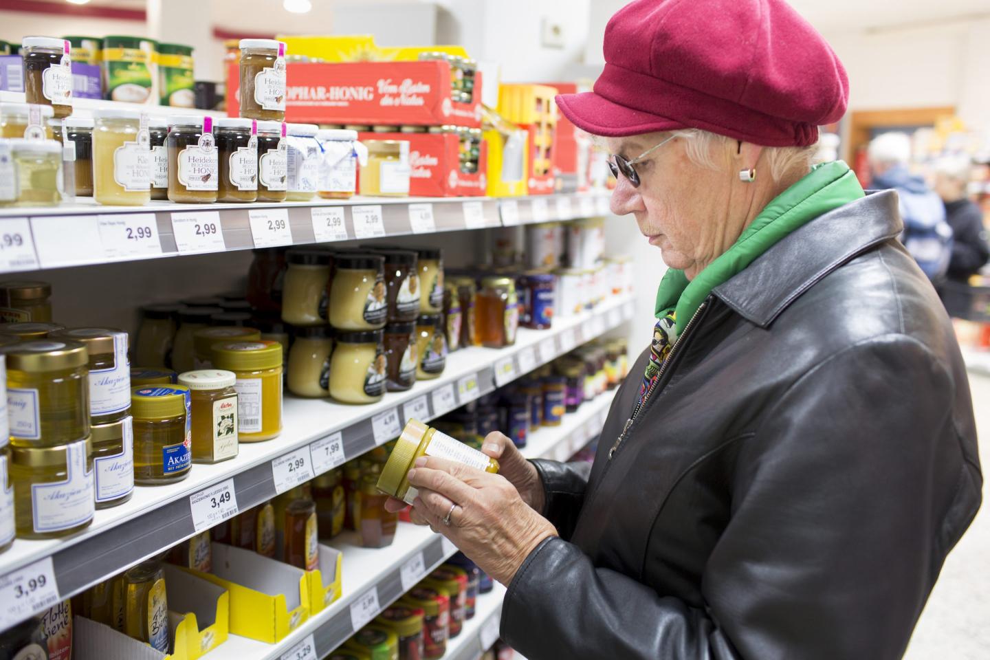 an old lady scanning a product at a grocery store aisle