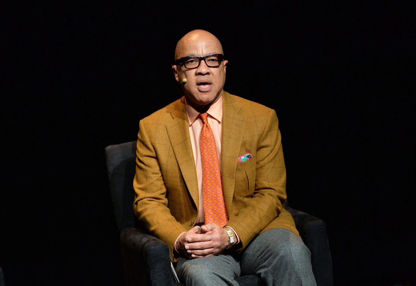 Darren Walker is sitting in a chair speaking at a conference.