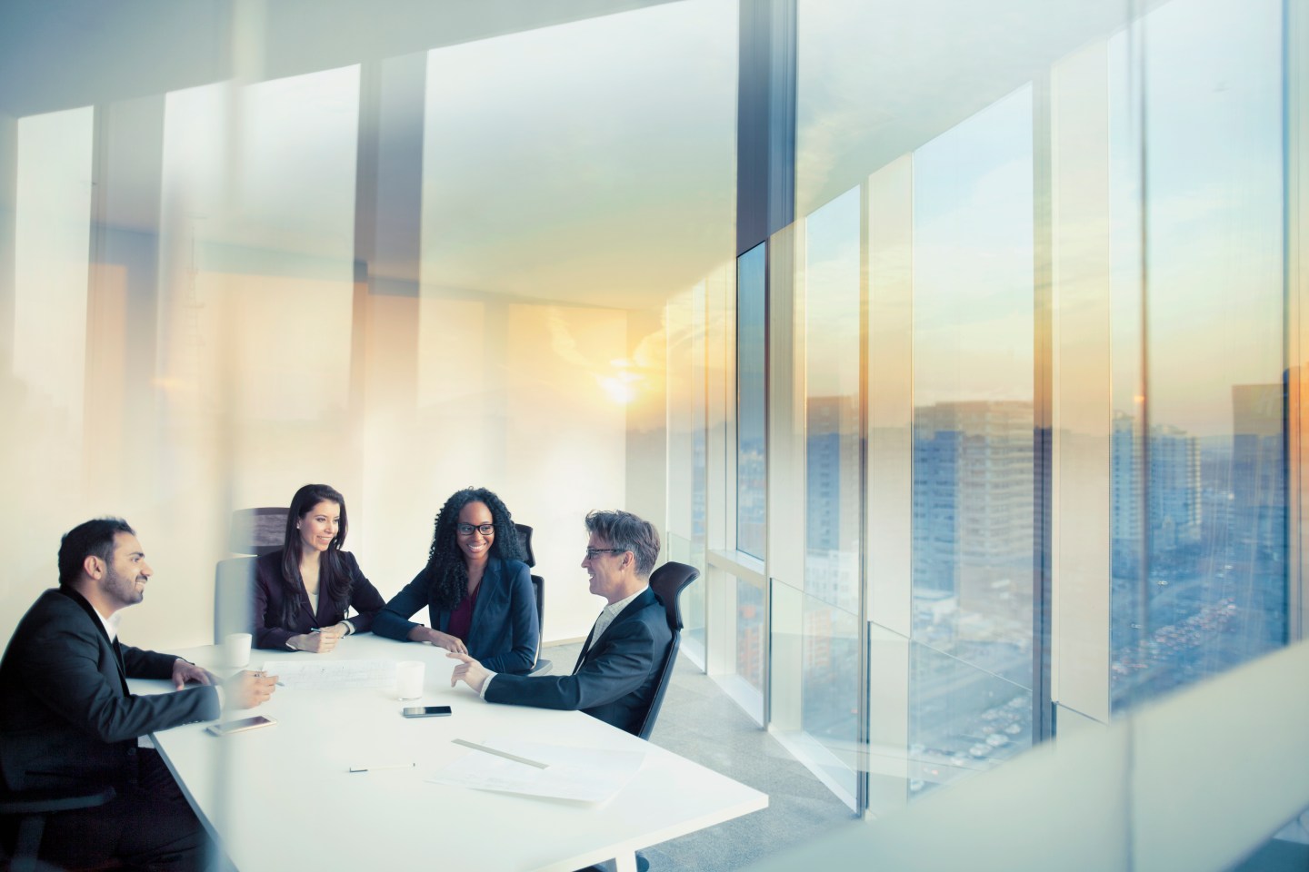office colleagues sit around a table in a sunlit room