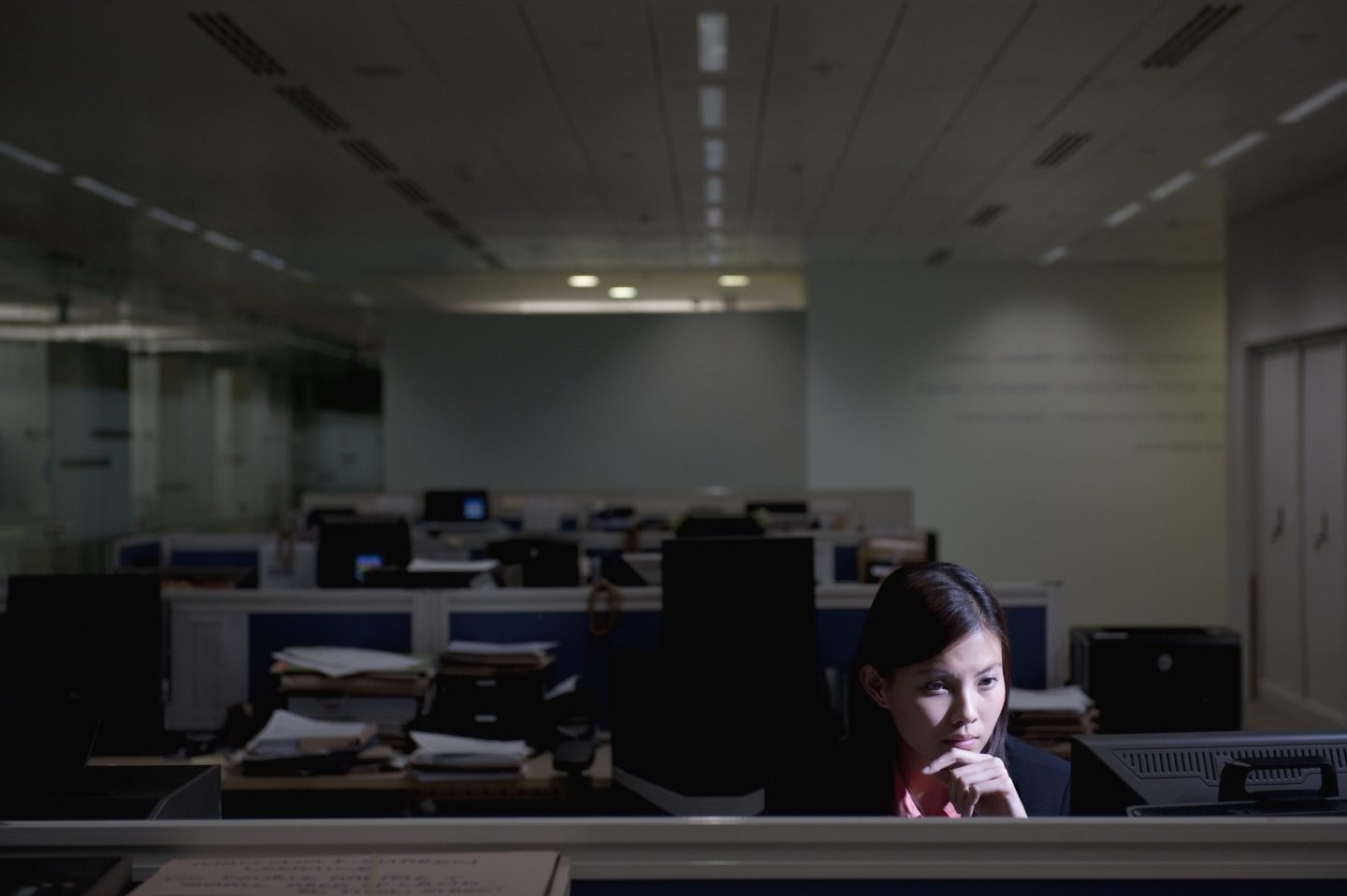 Woman sitting in an empty dark office along