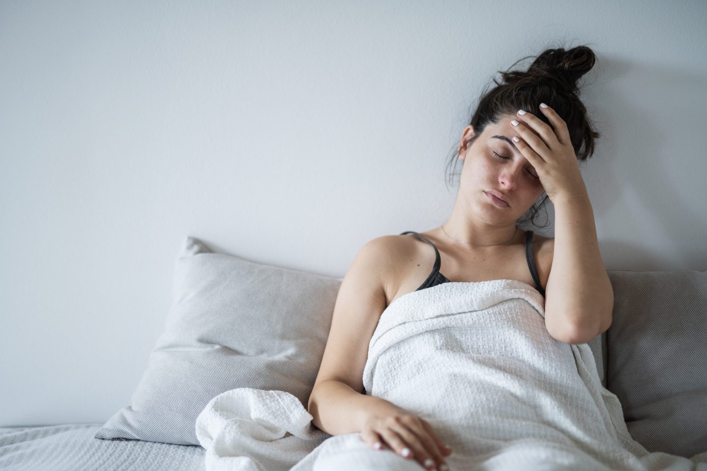 Young woman having a fever. She is holding her head because of a headache.